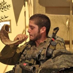 soldier blowing shofar at wall